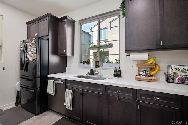 kitchen featuring black fridge, dishwasher, light countertops, and a sink