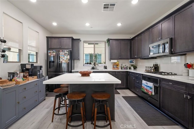 kitchen with dark brown cabinets, visible vents, black appliances, and a breakfast bar area