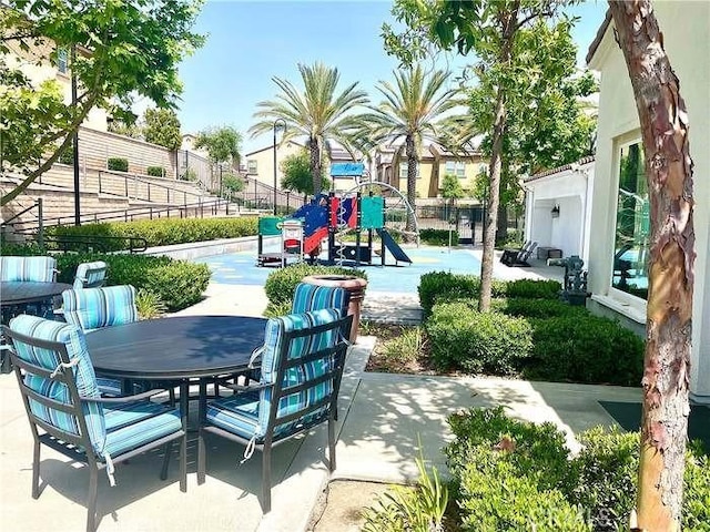 view of patio featuring outdoor dining space, a playground, and fence