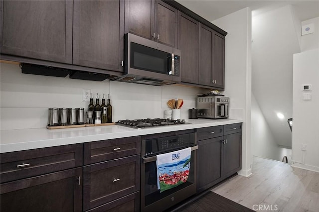 kitchen with baseboards, light wood finished floors, stainless steel appliances, dark brown cabinetry, and light countertops