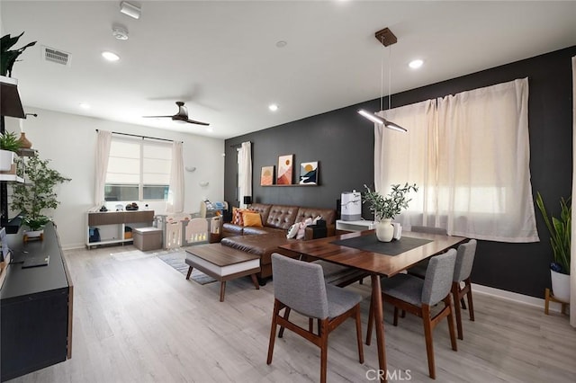 dining space featuring a ceiling fan, visible vents, light wood finished floors, and baseboards