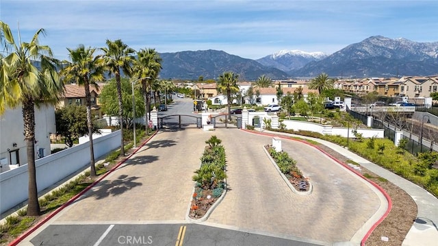 view of street featuring a gate, curbs, a residential view, a gated entry, and a mountain view