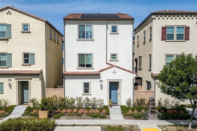 view of front of property with stucco siding, solar panels, and a tiled roof