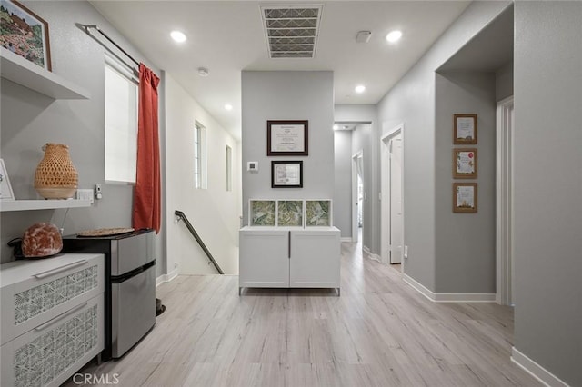 corridor featuring visible vents, light wood finished floors, baseboards, recessed lighting, and an upstairs landing