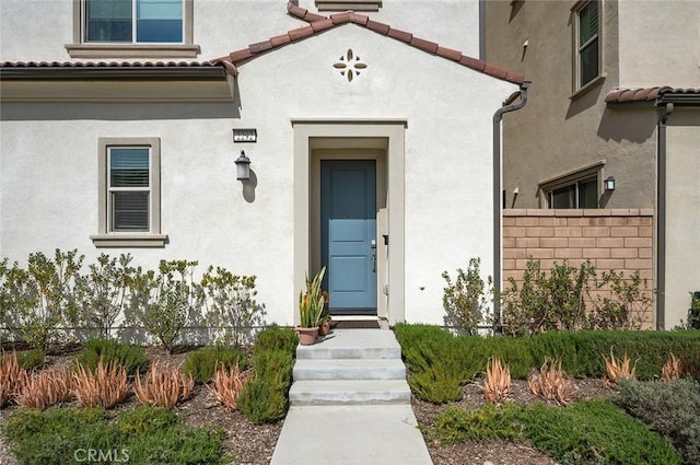 property entrance with a tile roof and stucco siding