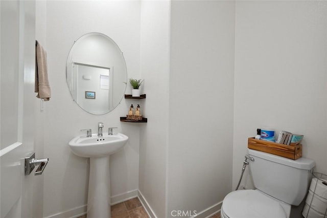 half bath with a sink, baseboards, and toilet