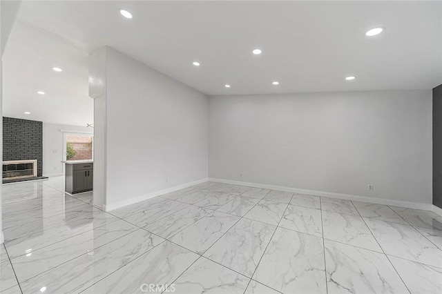 spare room featuring recessed lighting, baseboards, marble finish floor, and a fireplace