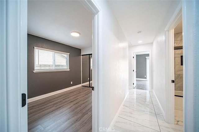 hallway featuring marble finish floor and baseboards