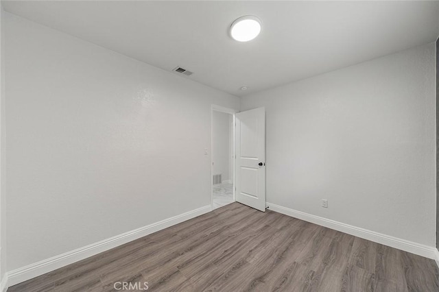 unfurnished room featuring visible vents, baseboards, and wood finished floors