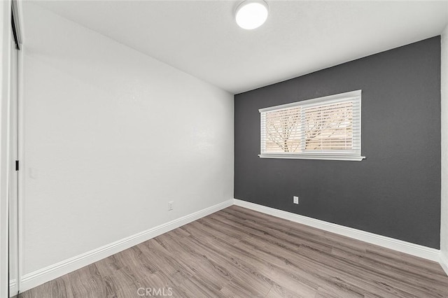 spare room featuring baseboards and wood finished floors