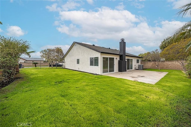 back of house with a patio, a yard, a fenced backyard, a chimney, and stucco siding