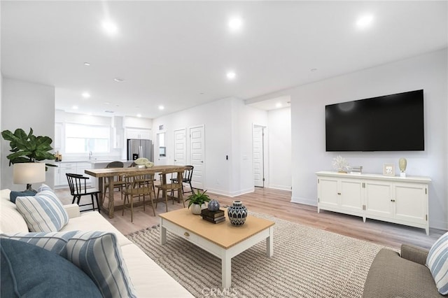 living area featuring recessed lighting, baseboards, and light wood-style floors