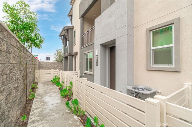 view of property exterior featuring stucco siding, central air condition unit, elevator, and a fenced backyard