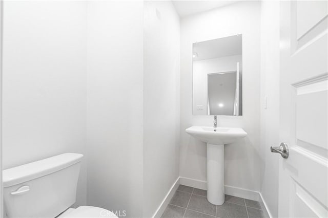 half bathroom featuring tile patterned floors, toilet, and baseboards