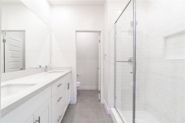 full bathroom with a shower stall, toilet, double vanity, tile patterned floors, and a sink