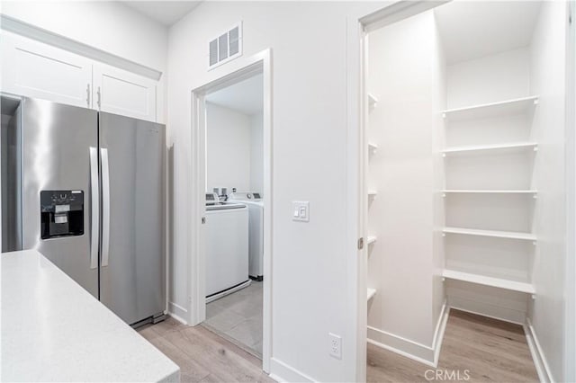 kitchen with visible vents, light wood finished floors, light countertops, stainless steel refrigerator with ice dispenser, and white cabinetry