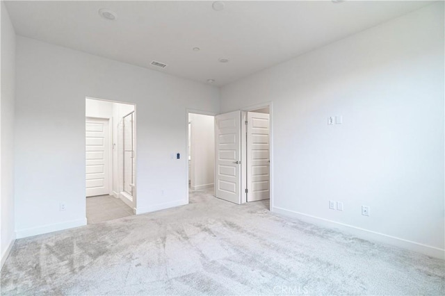 unfurnished bedroom featuring visible vents, carpet flooring, ensuite bath, and baseboards