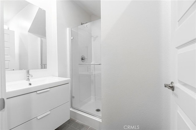 bathroom with tile patterned flooring, a shower stall, and vanity