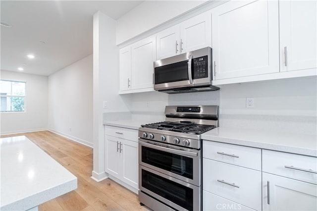 kitchen featuring light countertops, white cabinets, light wood finished floors, and stainless steel appliances