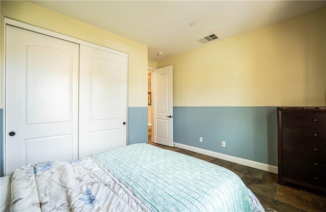 bedroom featuring a closet, visible vents, stone finish flooring, and baseboards