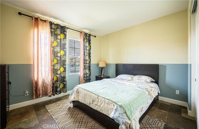 bedroom with baseboards and stone tile flooring