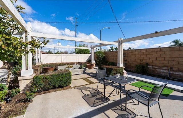 view of patio featuring outdoor dining area and fence