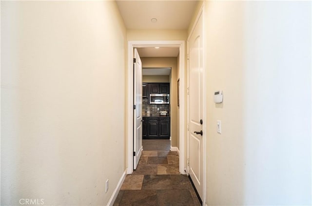 corridor with stone finish flooring and baseboards