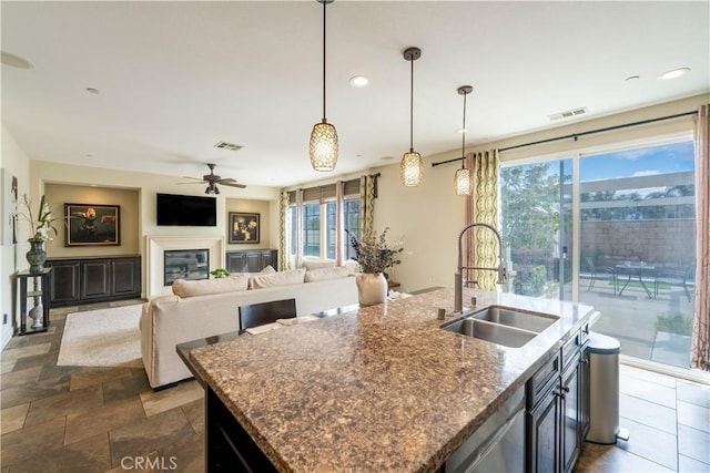 kitchen with decorative light fixtures, visible vents, a glass covered fireplace, and a sink