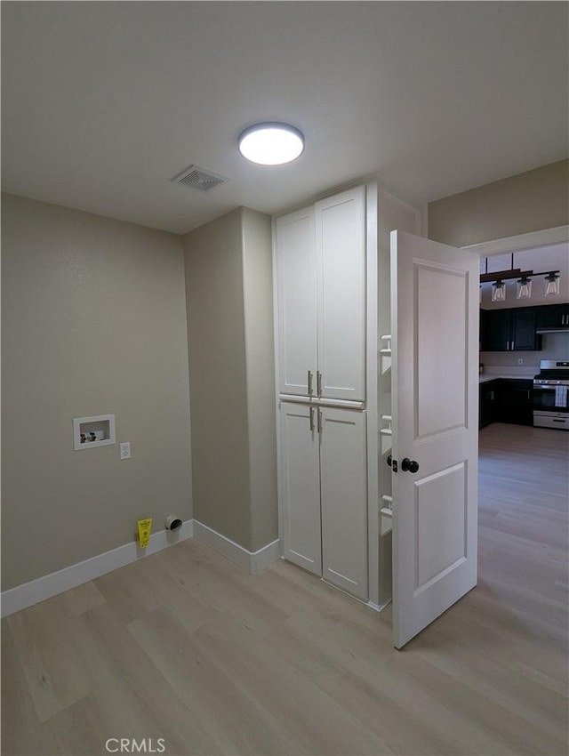 laundry area featuring cabinet space, hookup for a washing machine, light wood-type flooring, and baseboards