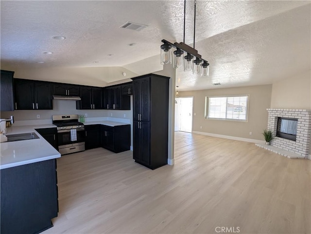 kitchen with visible vents, a fireplace, a sink, gas range, and open floor plan