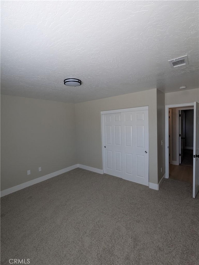 carpeted spare room featuring baseboards, visible vents, and a textured ceiling