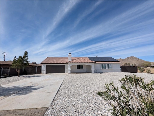 ranch-style house featuring a tile roof, fence, a garage, and a chimney