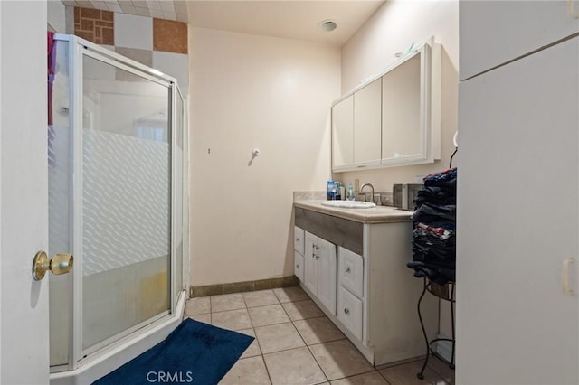 full bath featuring tile patterned flooring, vanity, a stall shower, and baseboards