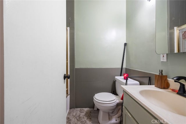 bathroom with toilet, tile walls, and vanity