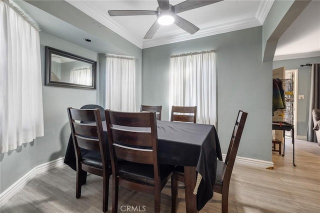 dining room with ceiling fan, baseboards, light wood finished floors, and ornamental molding