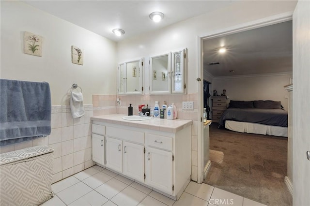 bathroom with tile walls, ensuite bath, vanity, and tile patterned flooring