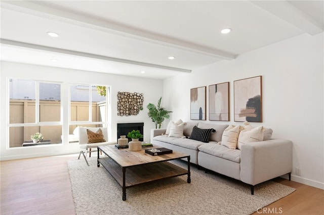 living area with beam ceiling, recessed lighting, a fireplace, and light wood-style floors