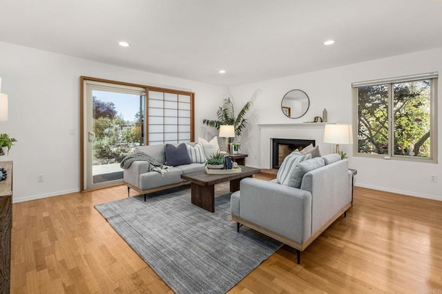 living room with recessed lighting, a healthy amount of sunlight, light wood-style flooring, and a fireplace