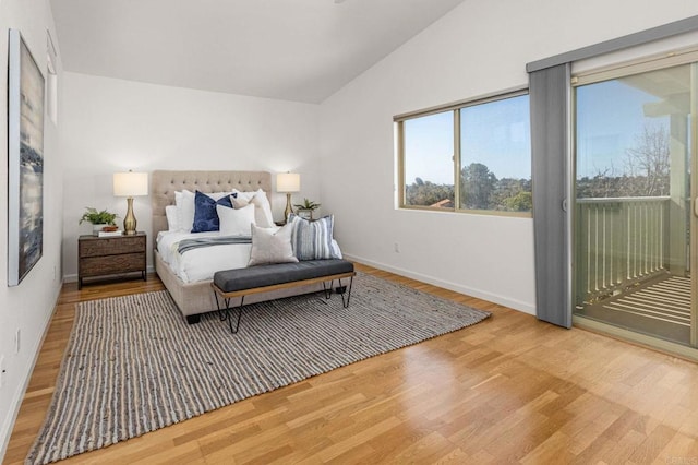 bedroom with wood finished floors, baseboards, lofted ceiling, and access to exterior