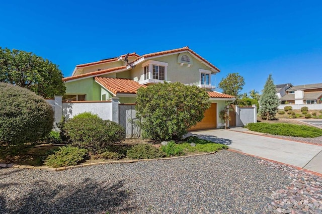 mediterranean / spanish house with a tiled roof, stucco siding, driveway, and fence