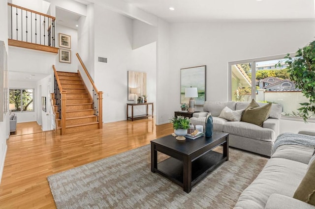 living room featuring visible vents, stairway, recessed lighting, wood finished floors, and high vaulted ceiling