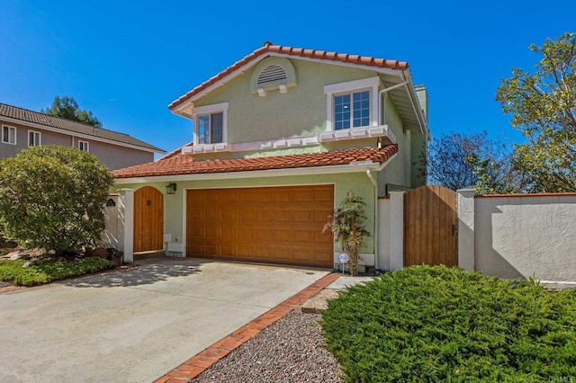 mediterranean / spanish-style home with stucco siding, a tiled roof, driveway, and a gate