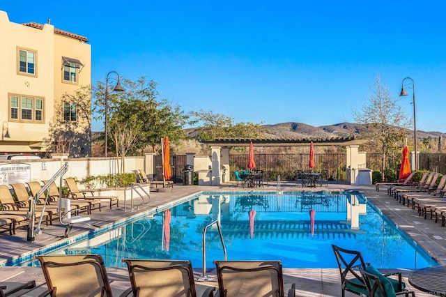 pool featuring a mountain view, a patio, and fence