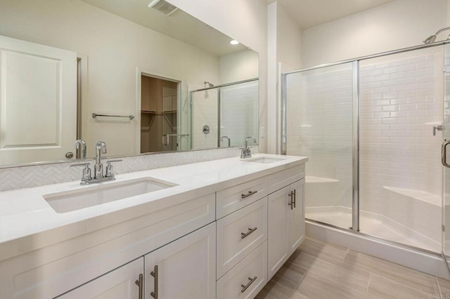 bathroom featuring a shower stall, double vanity, visible vents, and a sink