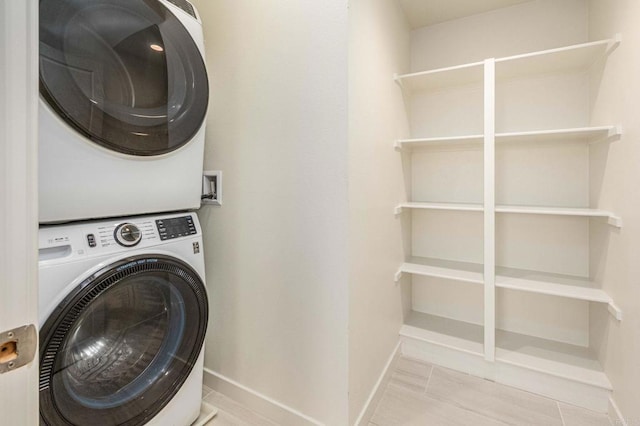 laundry room with baseboards, stacked washer and dryer, and laundry area