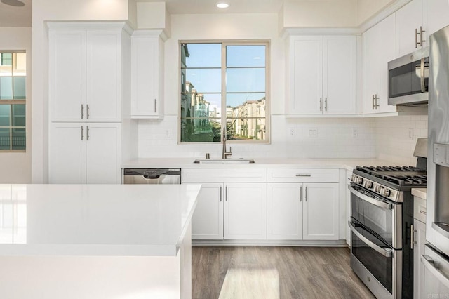 kitchen with light wood finished floors, a sink, light countertops, appliances with stainless steel finishes, and white cabinetry