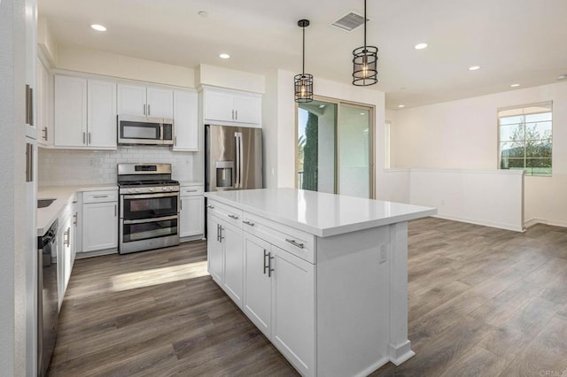 kitchen featuring visible vents, dark wood-style flooring, stainless steel appliances, white cabinetry, and tasteful backsplash