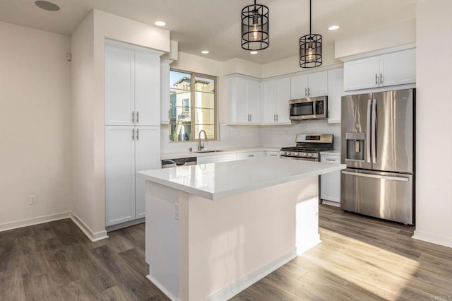 kitchen with white cabinets, a center island, appliances with stainless steel finishes, and a sink