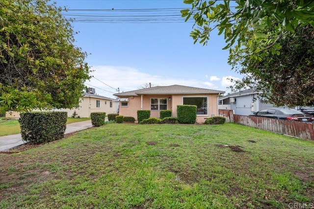 view of front of property featuring stucco siding, a front yard, and fence