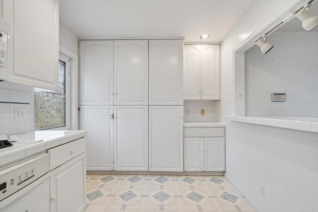 kitchen with tile countertops, light floors, and white cabinets